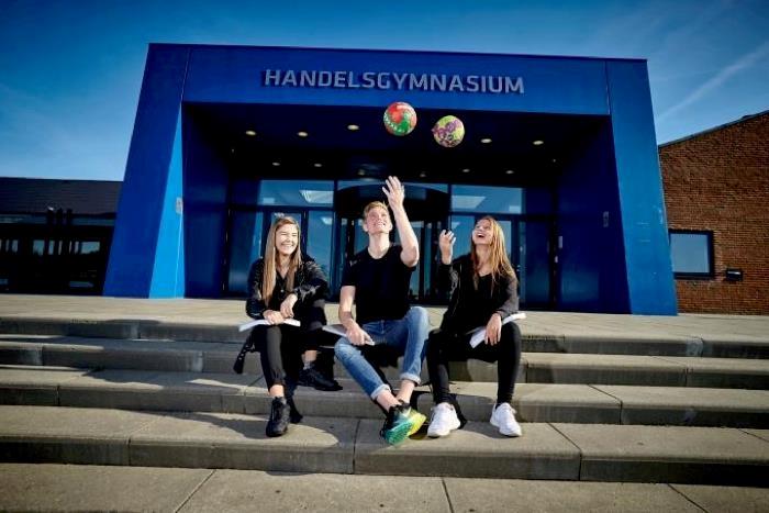 Tre unge sportsudøvere foran handelsgymnasiet